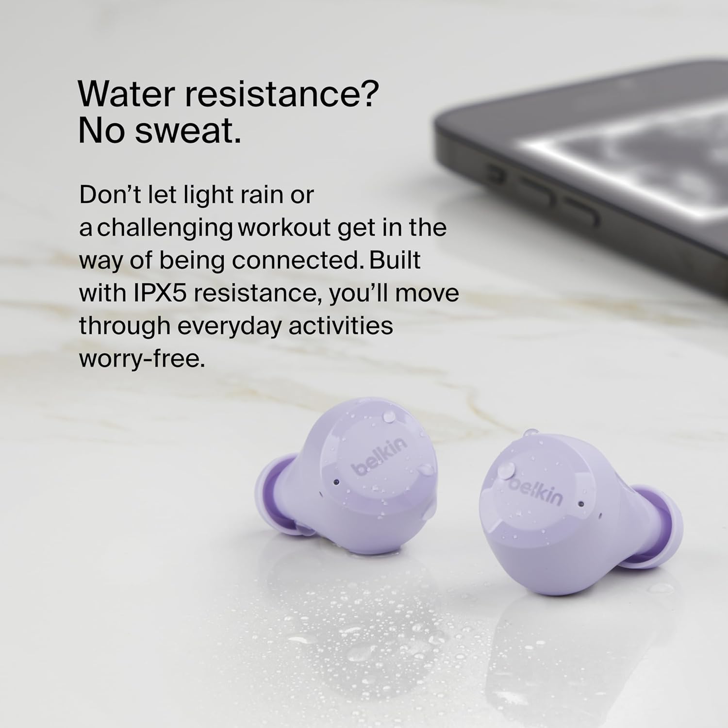 Two lavender Belkin SoundForm Bolt earbuds with water droplets on their surface, indicating water resistance.