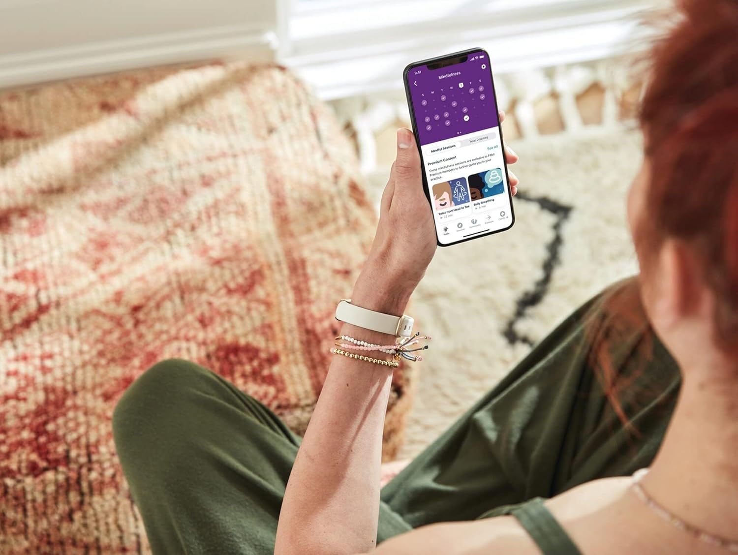 Πρόσωπο viewing Fitbit app on smartphone, showing wellness insights and activity data.