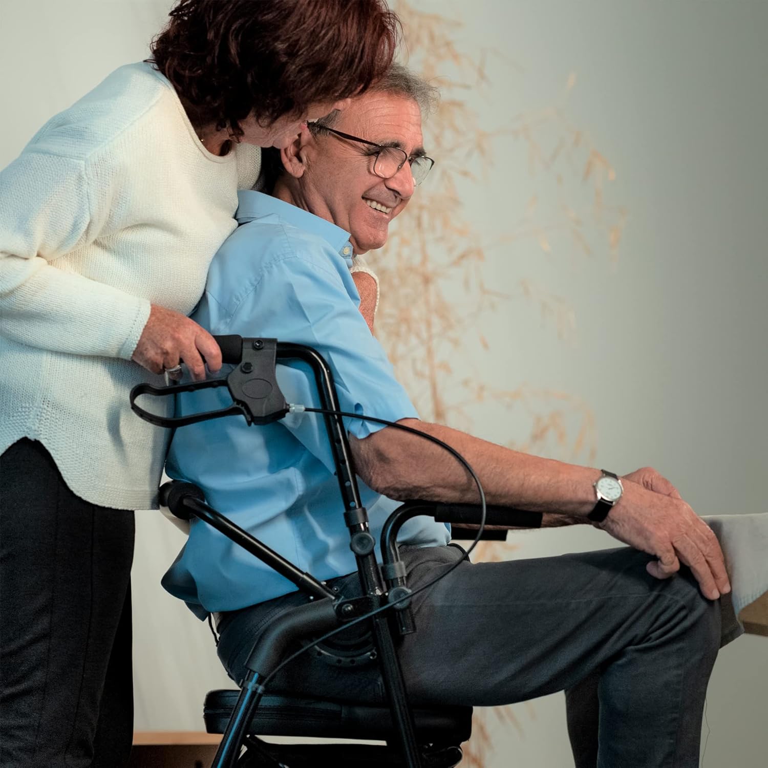 Hands demonstrating how to operate the hand brakes on the KMINA rollator, showing the squeeze and push-down motion.