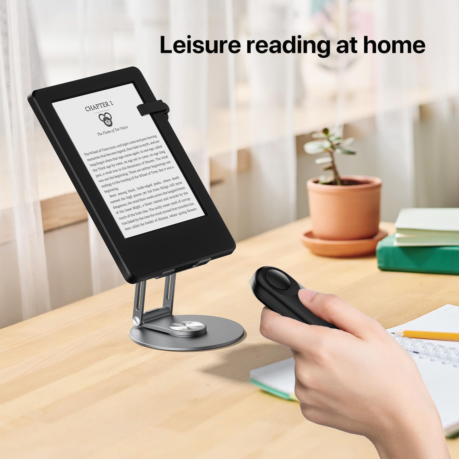 Person using the remote page turner while reading an e-reader on a desk stand.