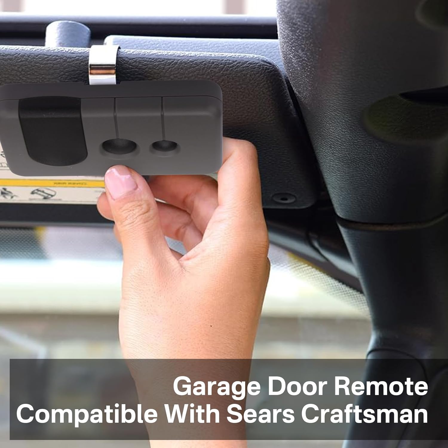 A hand holding the Earthtec garage door remote, clipped to a car's sun visor, demonstrating its use inside a vehicle.