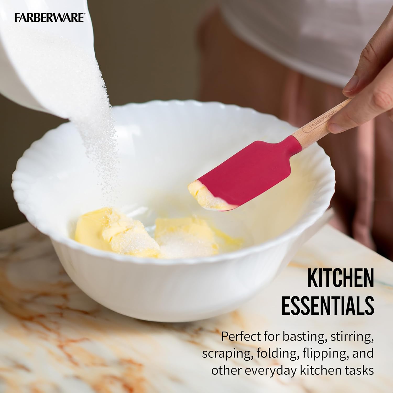 A hand using the red silicone spatula from the Farberware Mini Wood Baking Set to mix ingredients in a white bowl.