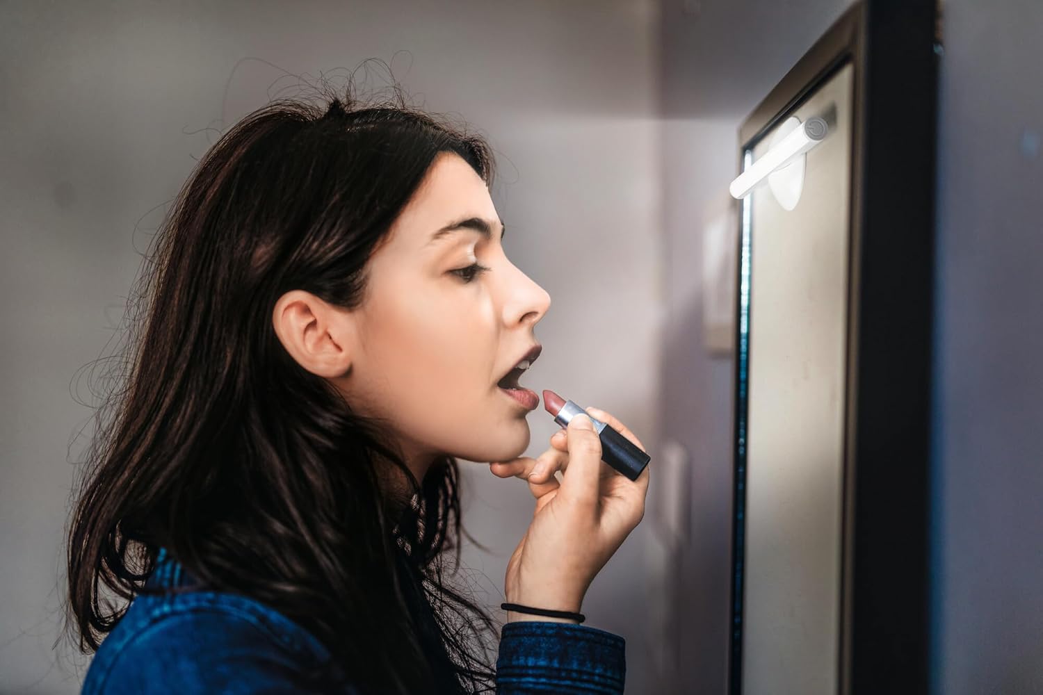 Woman applying makeup with OSRAM LEDSTIXX providing light