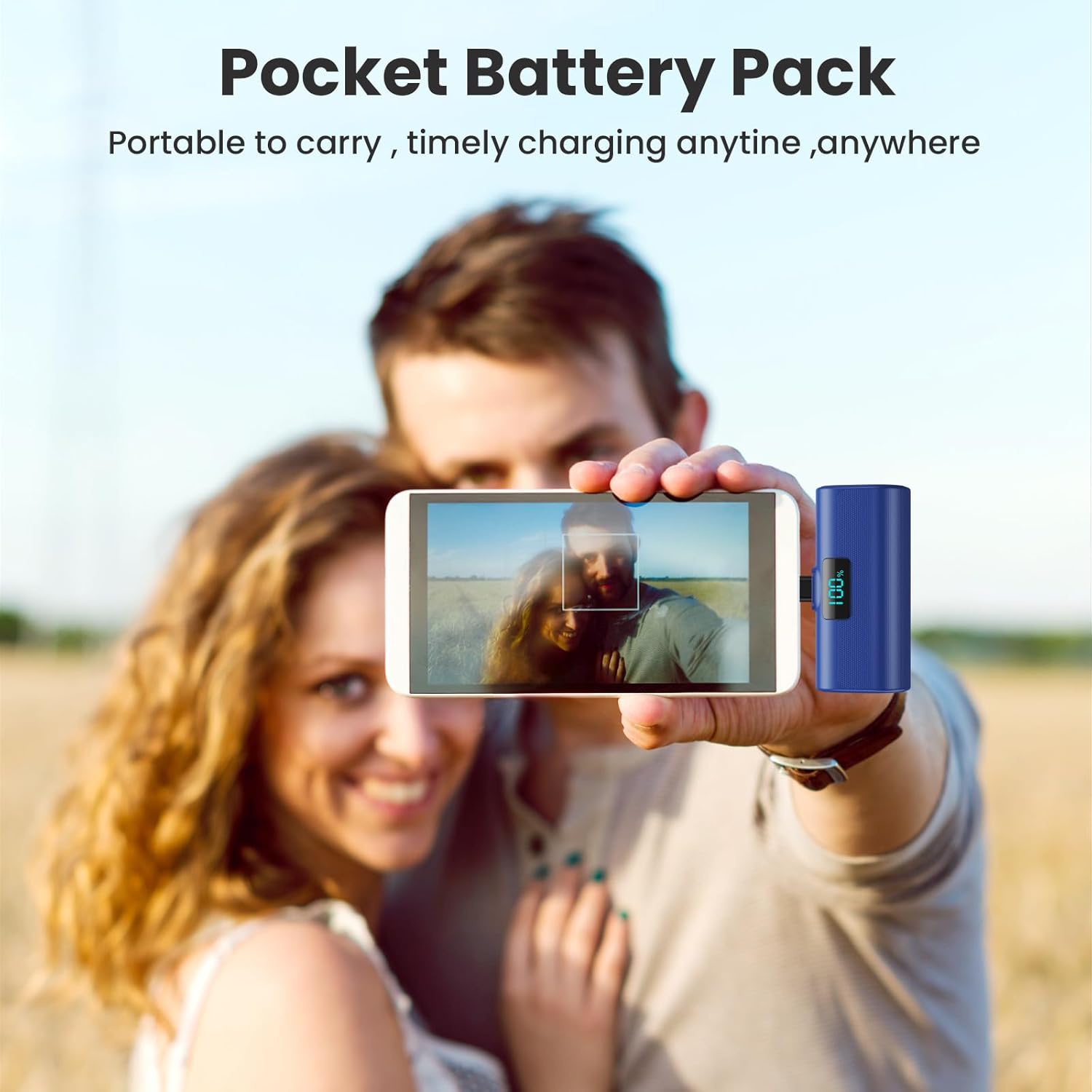 A person holding a blue HETP portable power bank connected to a smartphone, taking a selfie, demonstrating its pocket-sized convenience.