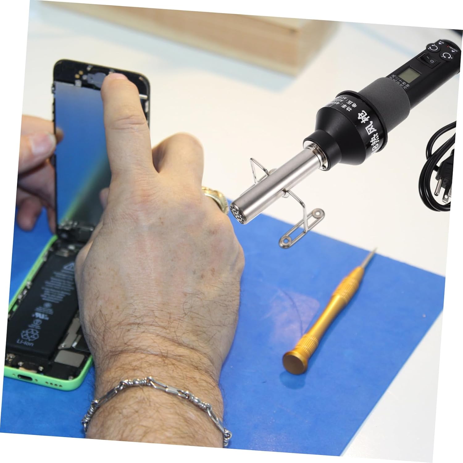 Heat gun being used for mobile phone repair, specifically on a screen assembly.