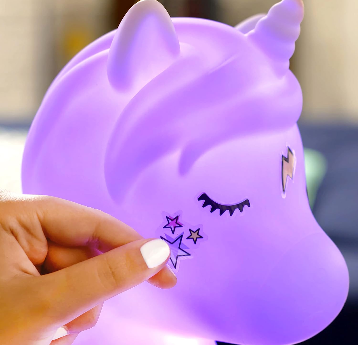 Hand applying a decorative sticker to the Unicorn Light Up Speaker.