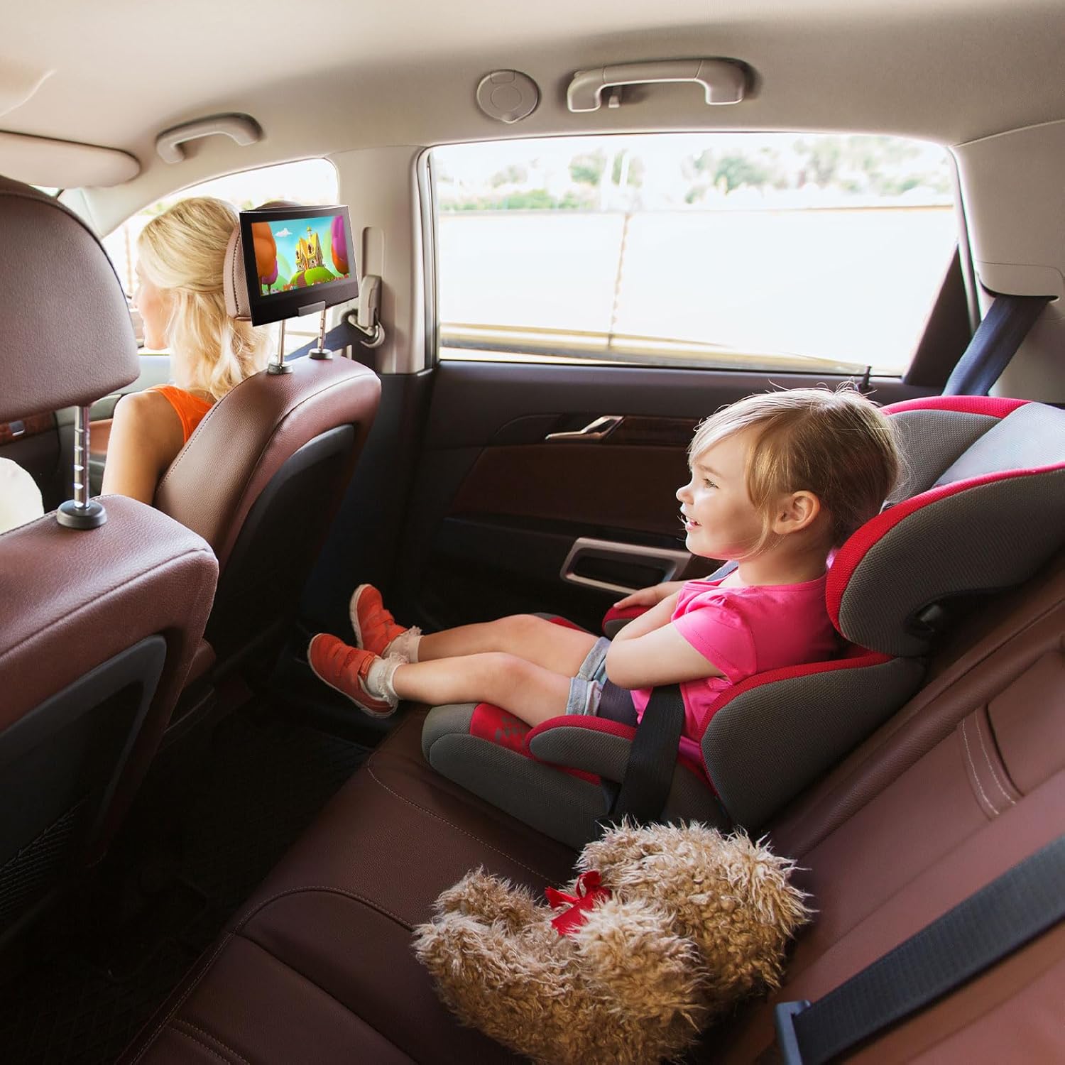 A child watching the SUNPIN Portable DVD Player mounted on the back of a car seat headrest.