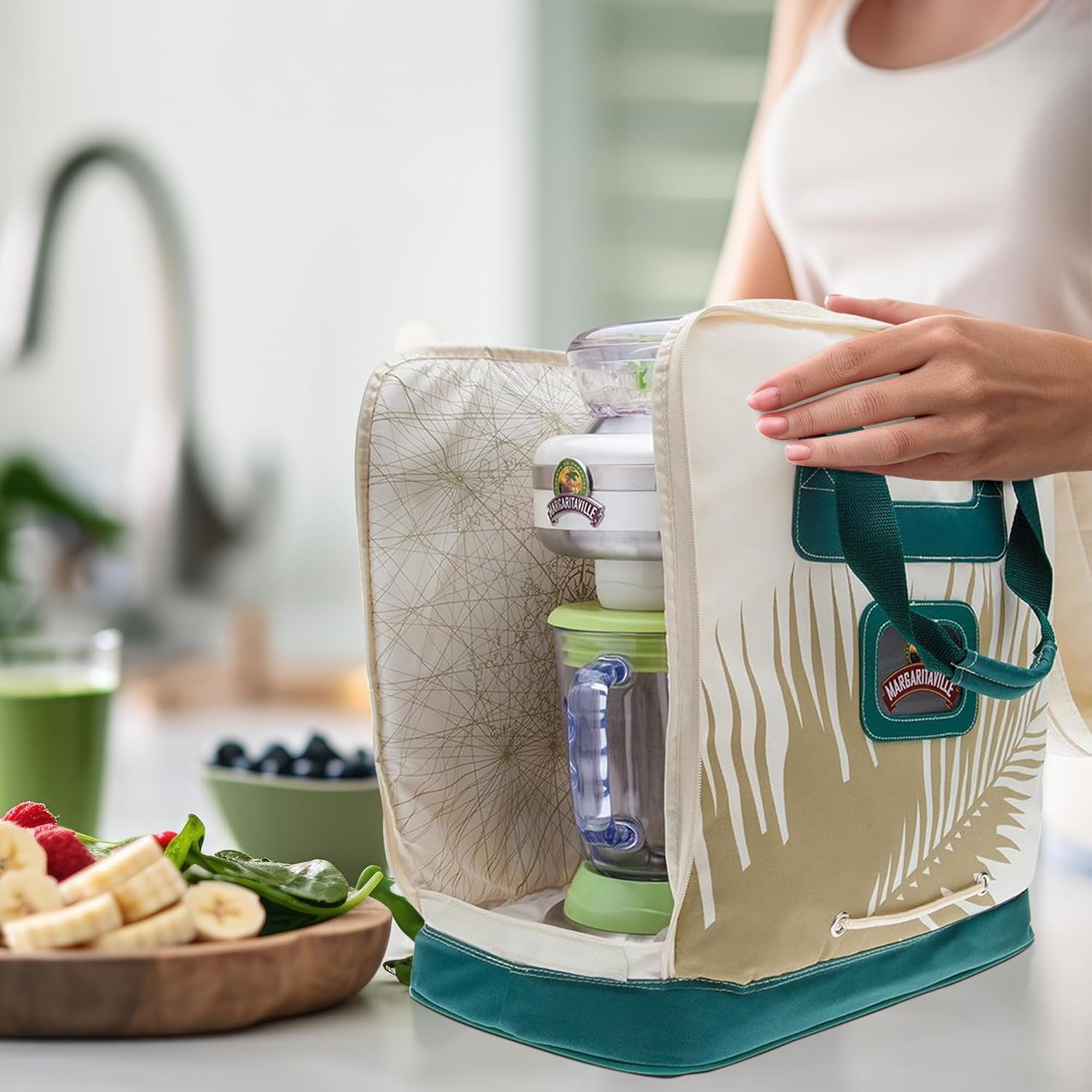 Person carefully placing a Margaritaville mixer into the open AD1200 Travel Bag on a kitchen counter.