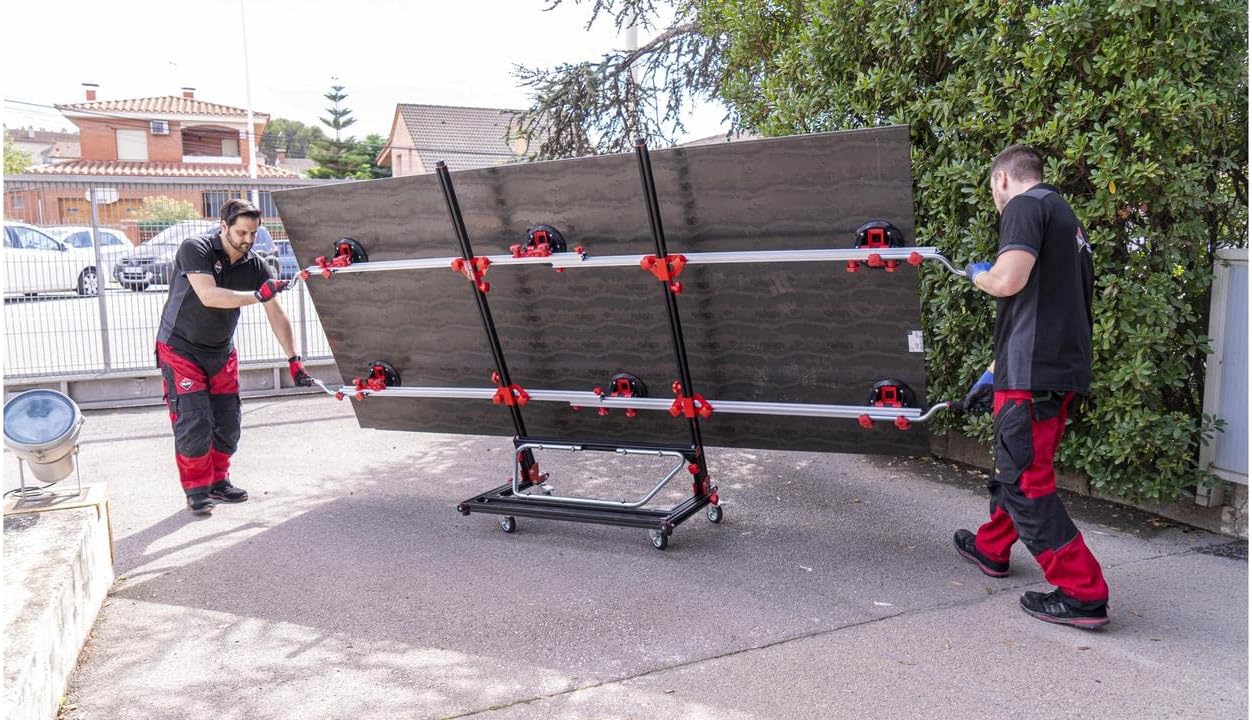 Two workers using the RUBI Slim Easy Trans Plus to lift and transport a large dark-colored slab outdoors, with the tool attached to the slab.