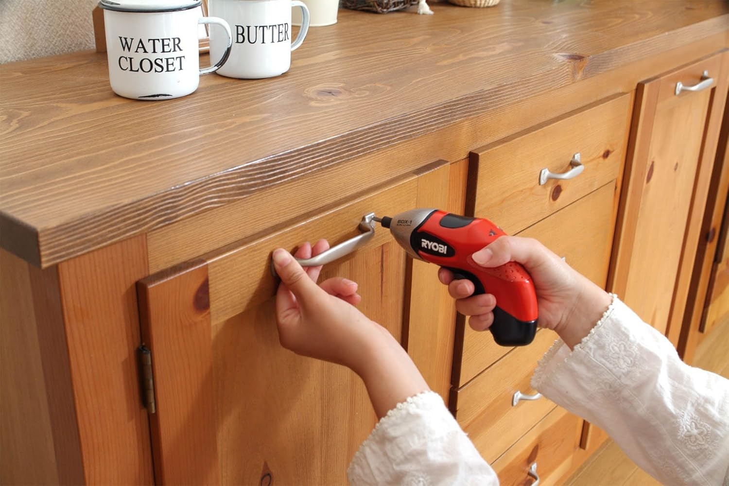 Woman using Kyocera Ryobi BDX-1 screwdriver to install a cabinet handle
