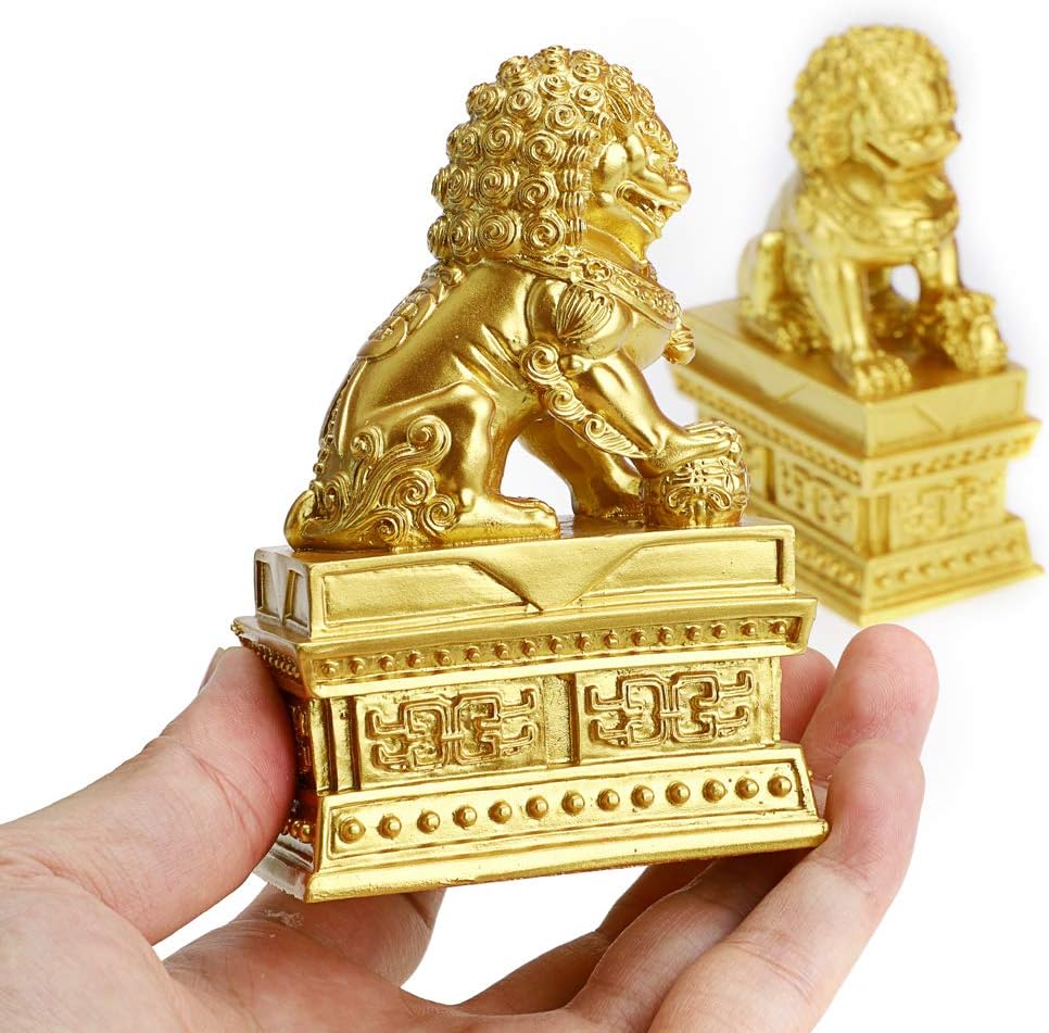 A hand holding a Foo Dog statue, showing its size relative to a human hand.