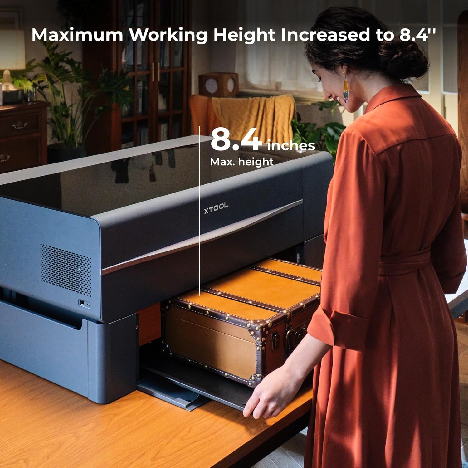 A woman placing a large, thick wooden trunk into an xTool P2 laser cutter elevated by the Riser Base, demonstrating increased working height.