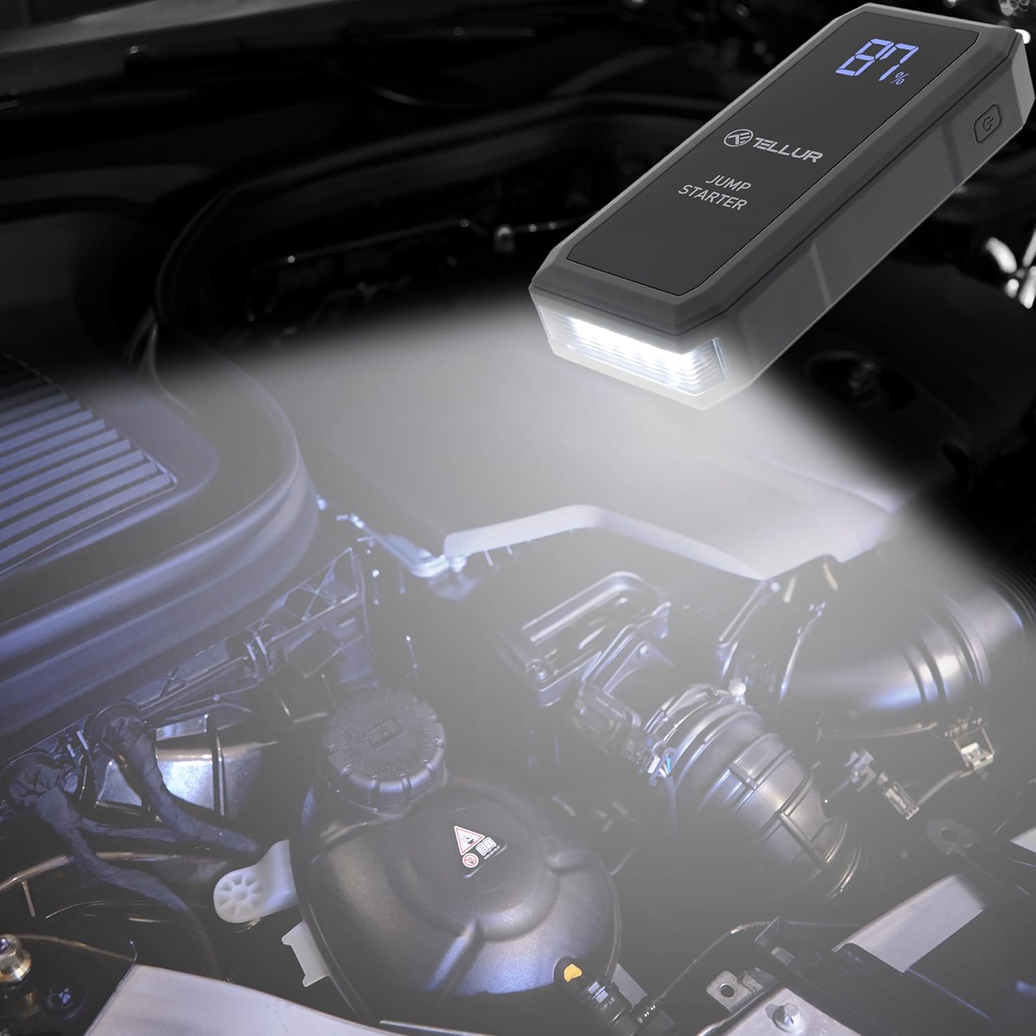 TELLUR Portable Jump Starter with its LED light illuminated, shining into a car engine bay.