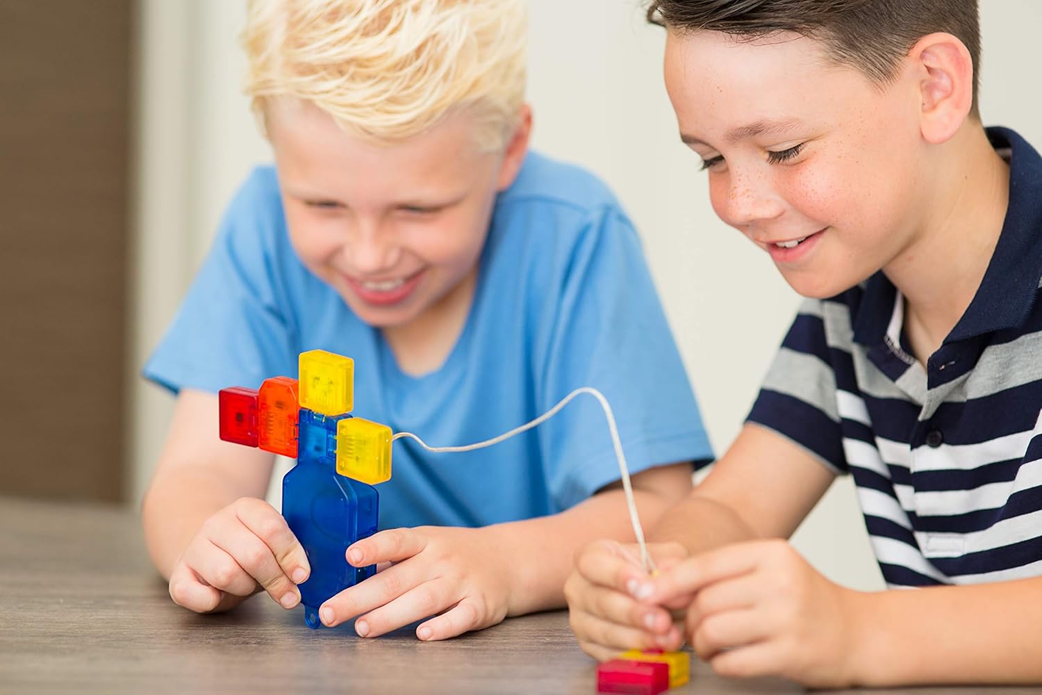 Two children assembling Logiblocs, connecting different colored blocks to a blue power base.