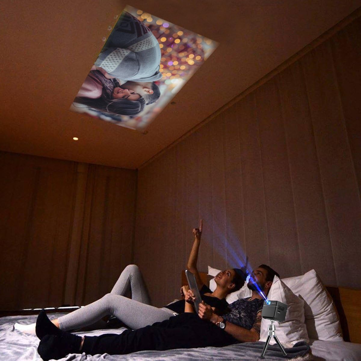 Couple watching a movie projected onto a bedroom ceiling by the ExquizOn S6 projector.