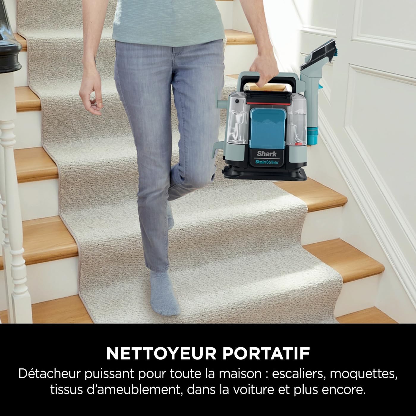 Person carrying the Shark StainStriker up a flight of carpeted stairs, highlighting its portability