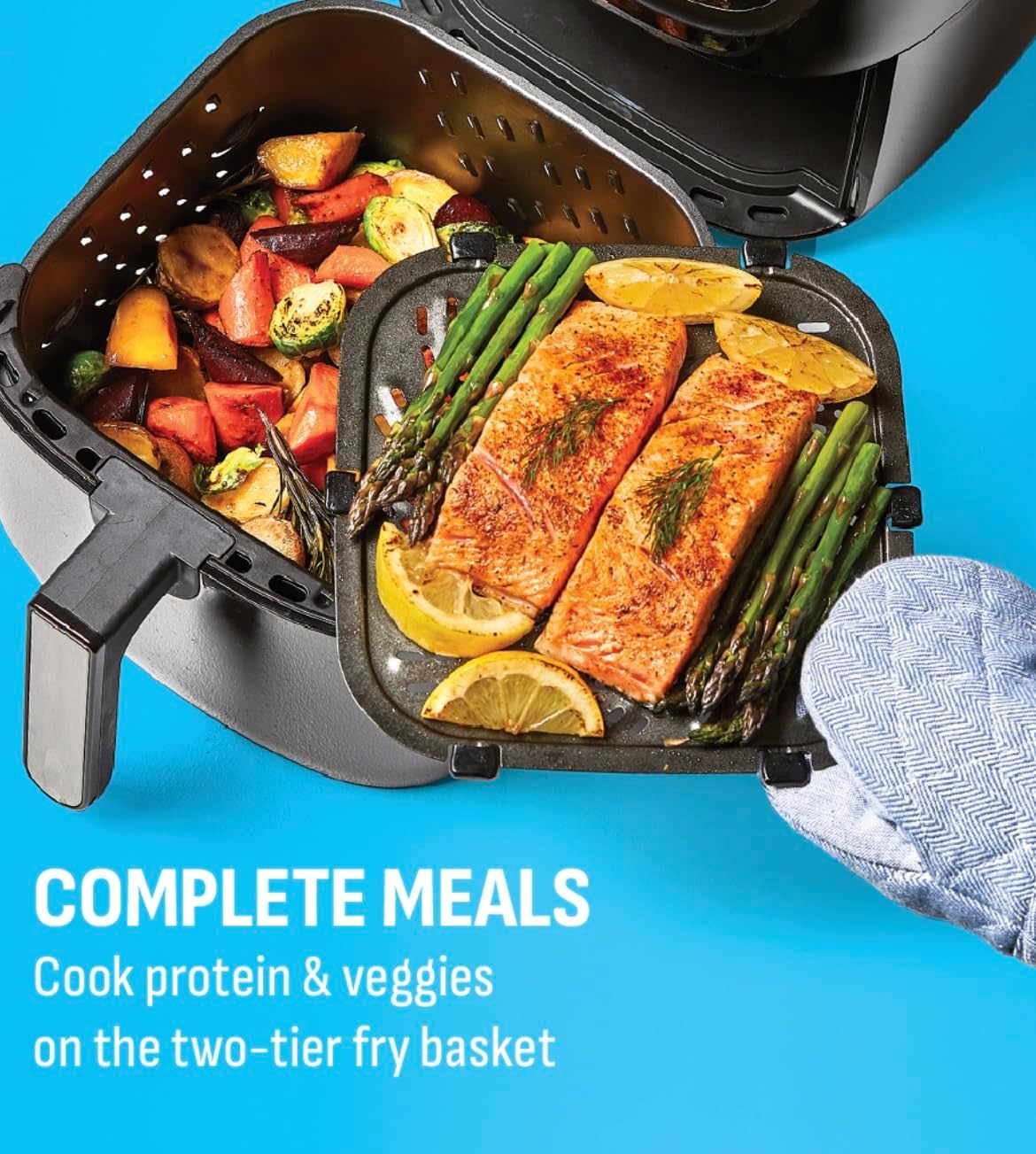 Air fryer basket with two tiers, cooking salmon on top and vegetables below