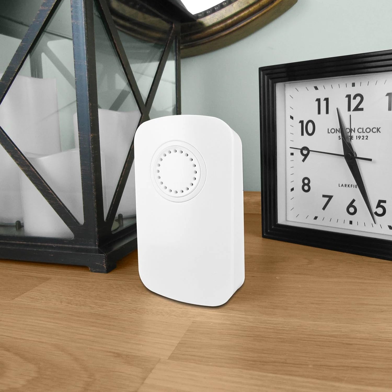 Uni-Com S/Chime Portable Door Chime on a wooden surface next to a clock