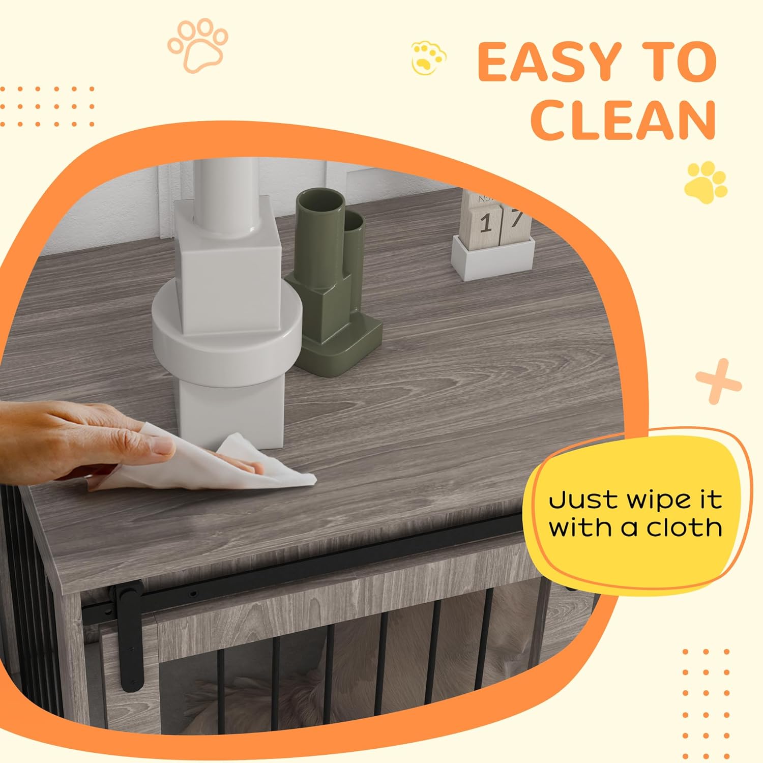 A hand wiping the top surface of the dog crate furniture with a cloth.