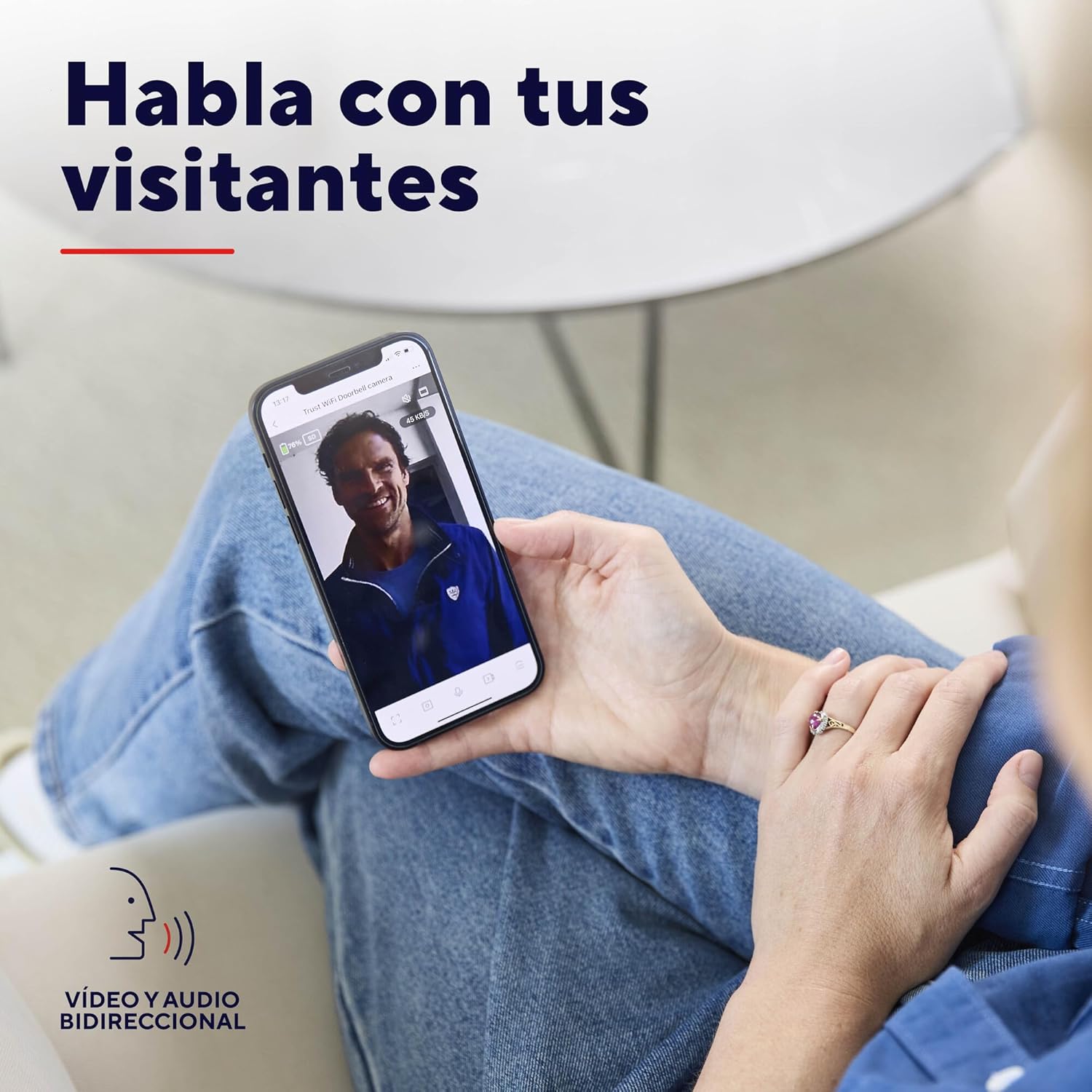 Kobieta viewing a visitor on her smartphone via the Trust Video Doorbell app, demonstrating two-way audio.