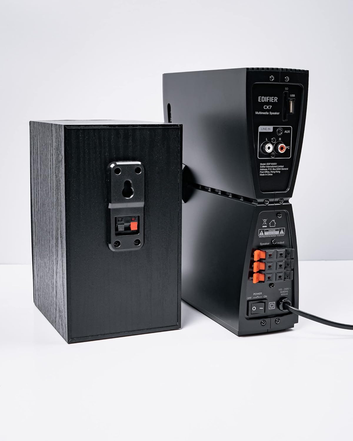 Арткы view of the Edifier CX7 control unit showing various input and output ports, including speaker terminals, and a satellite speaker with its connection terminals.