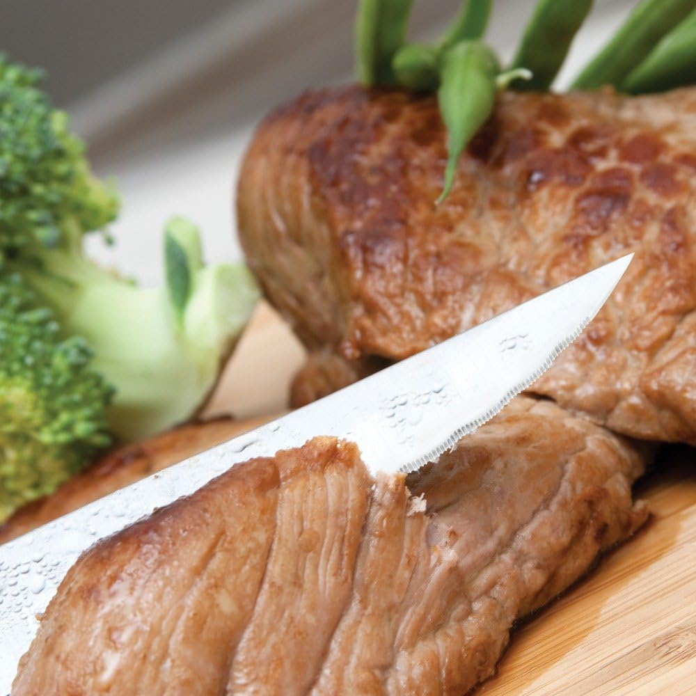 Knife cutting a piece of steak, demonstrating the serrated edge.