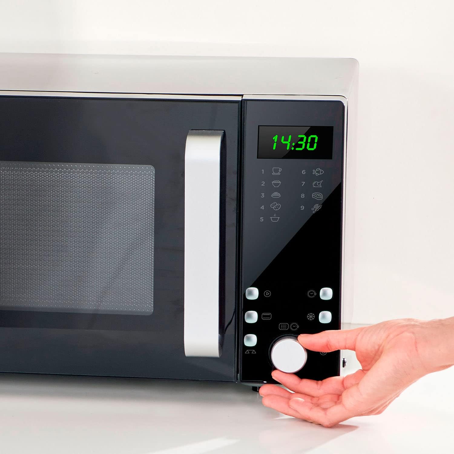 Hand adjusting the control knob on the BLACK+DECKER BXMZ900E microwave
