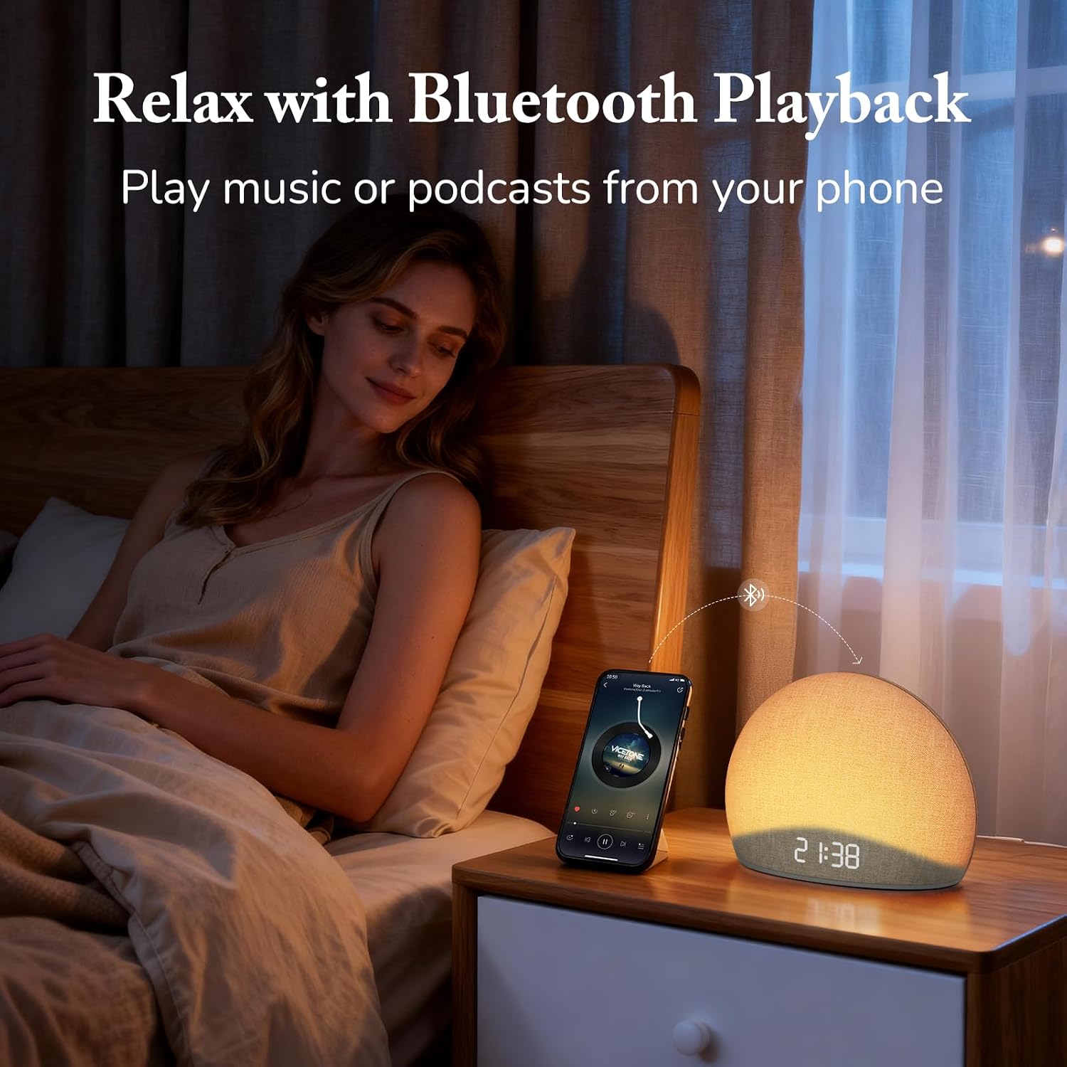 A person relaxing in bed while streaming music via Bluetooth to the HOUSBAY Sunrise Alarm Clock.