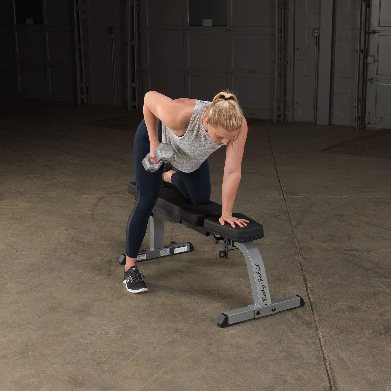Woman performing a one-arm dumbbell row using the Body-Solid GFI21 bench.