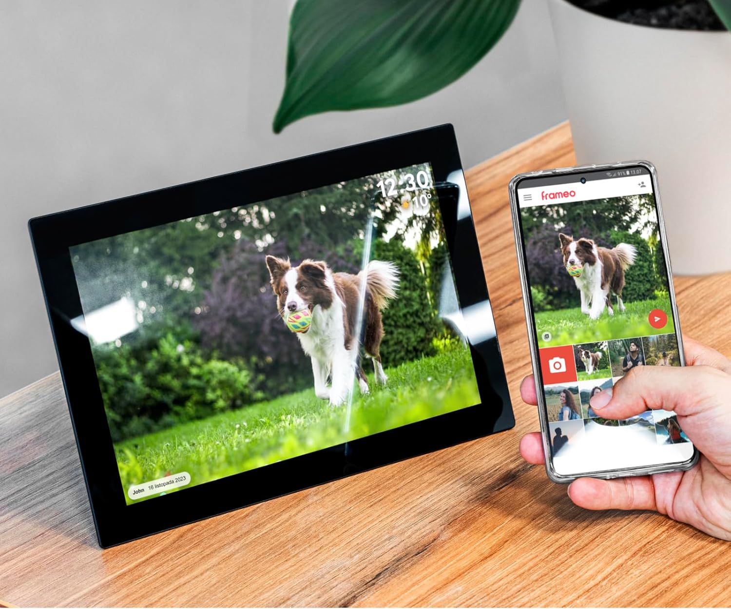 Digital photo frame next to a smartphone displaying the Frameo app interface
