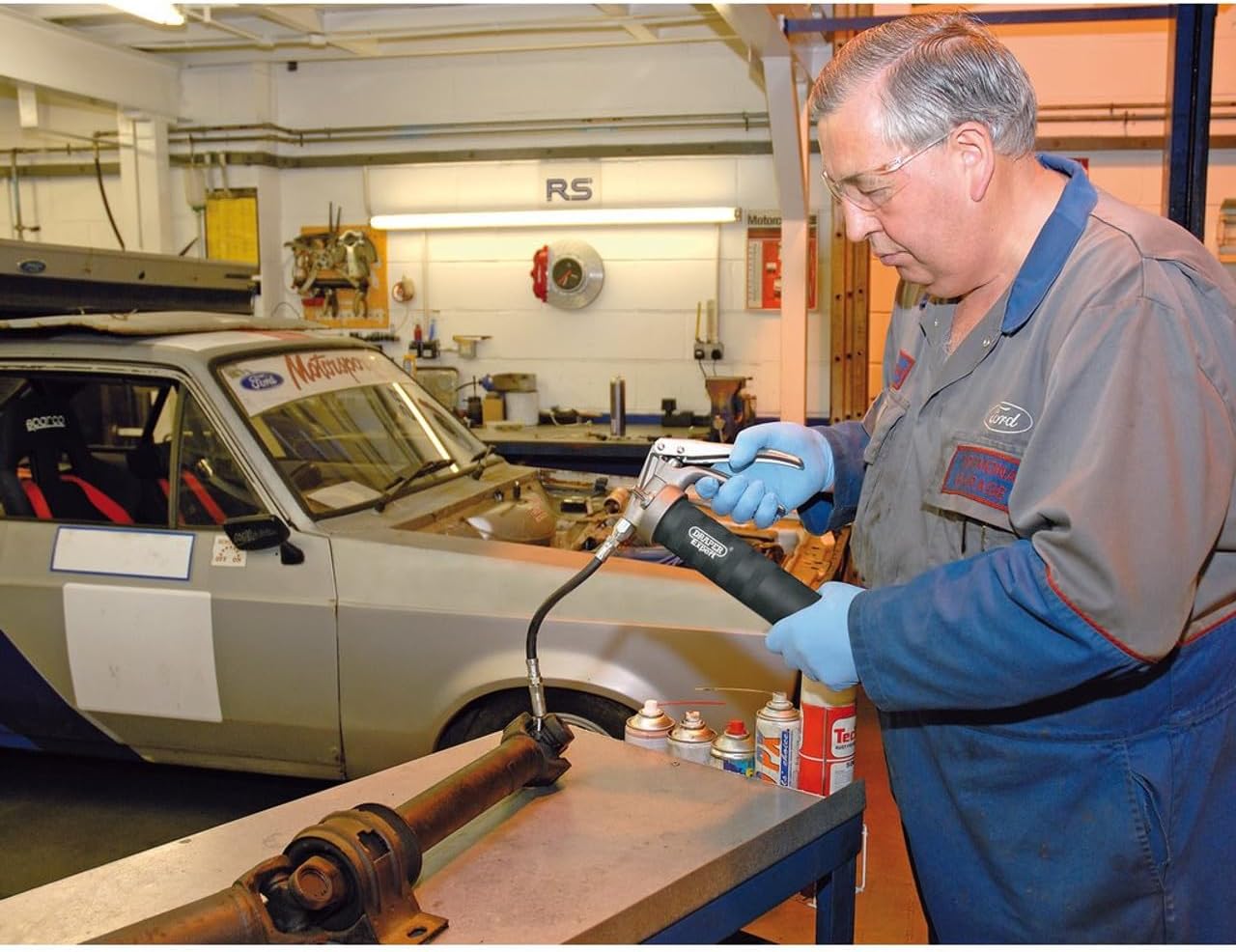 Mechanic using Draper grease gun on a vehicle driveshaft