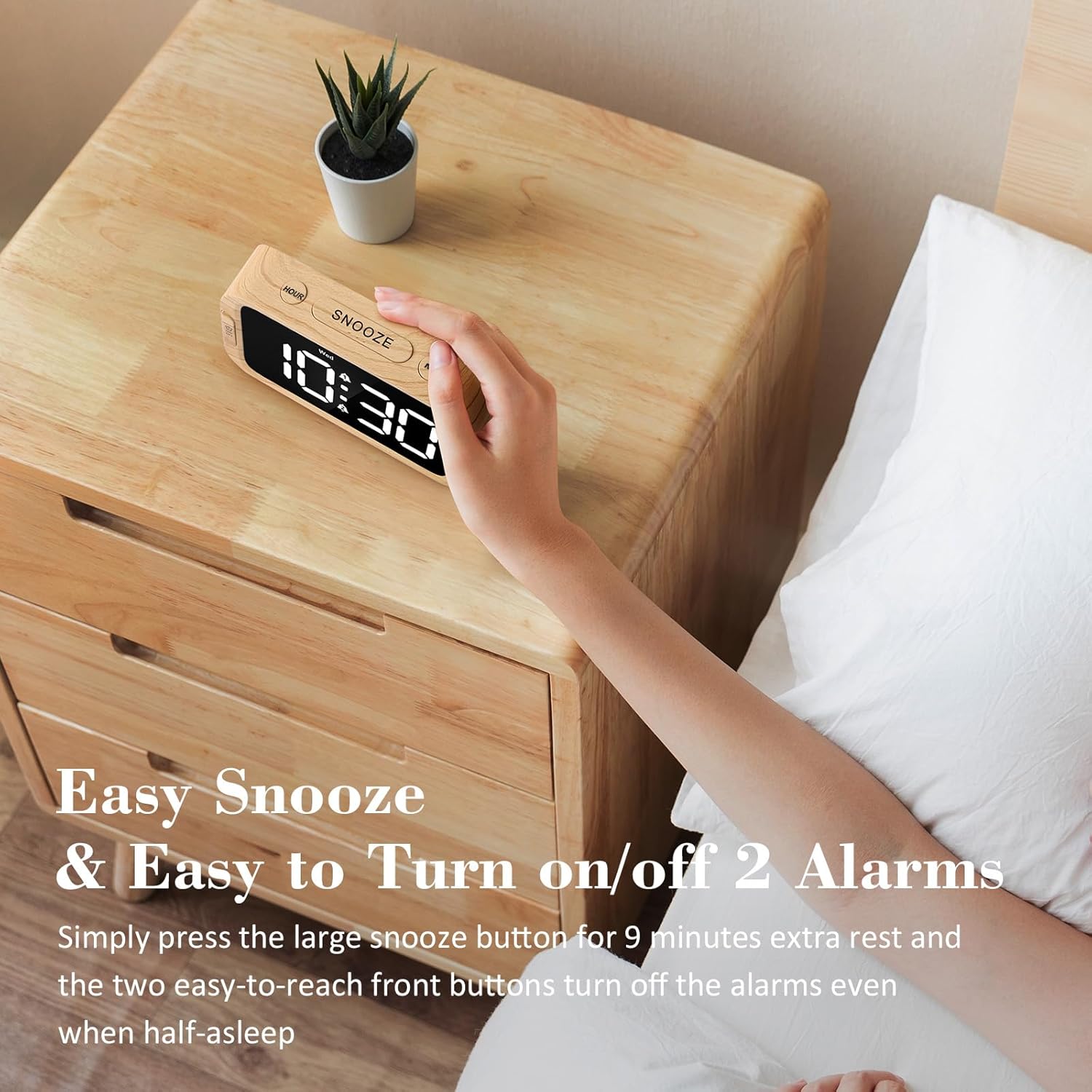 A hand pressing the large SNOOZE button on top of the alarm clock