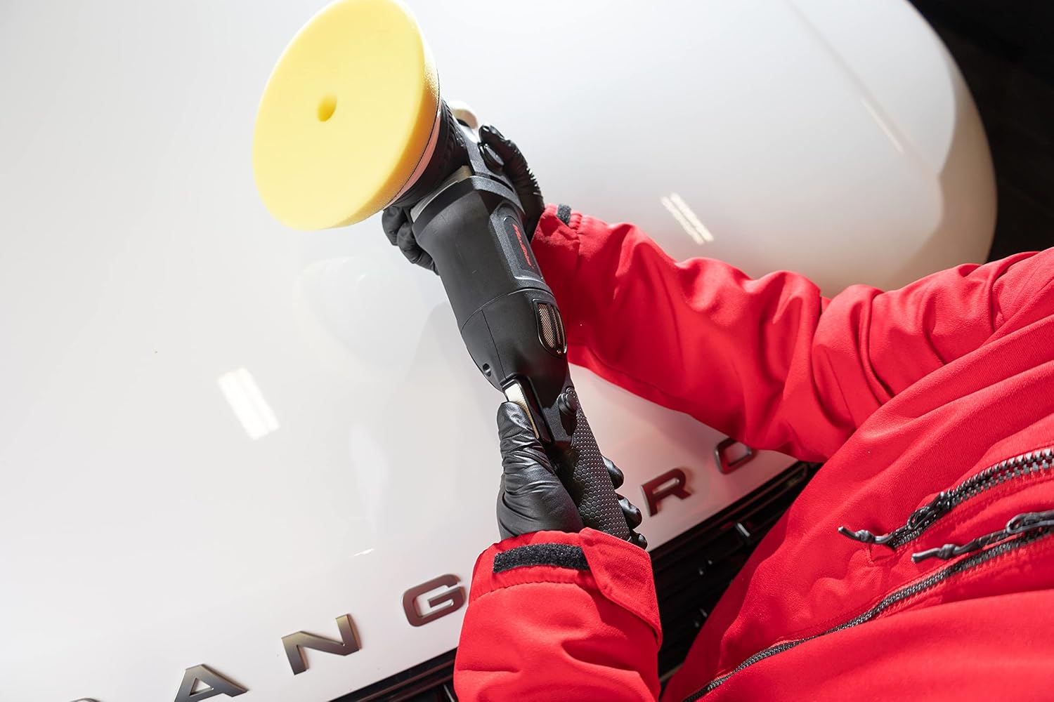 User holding the polisher with both hands on a car panel