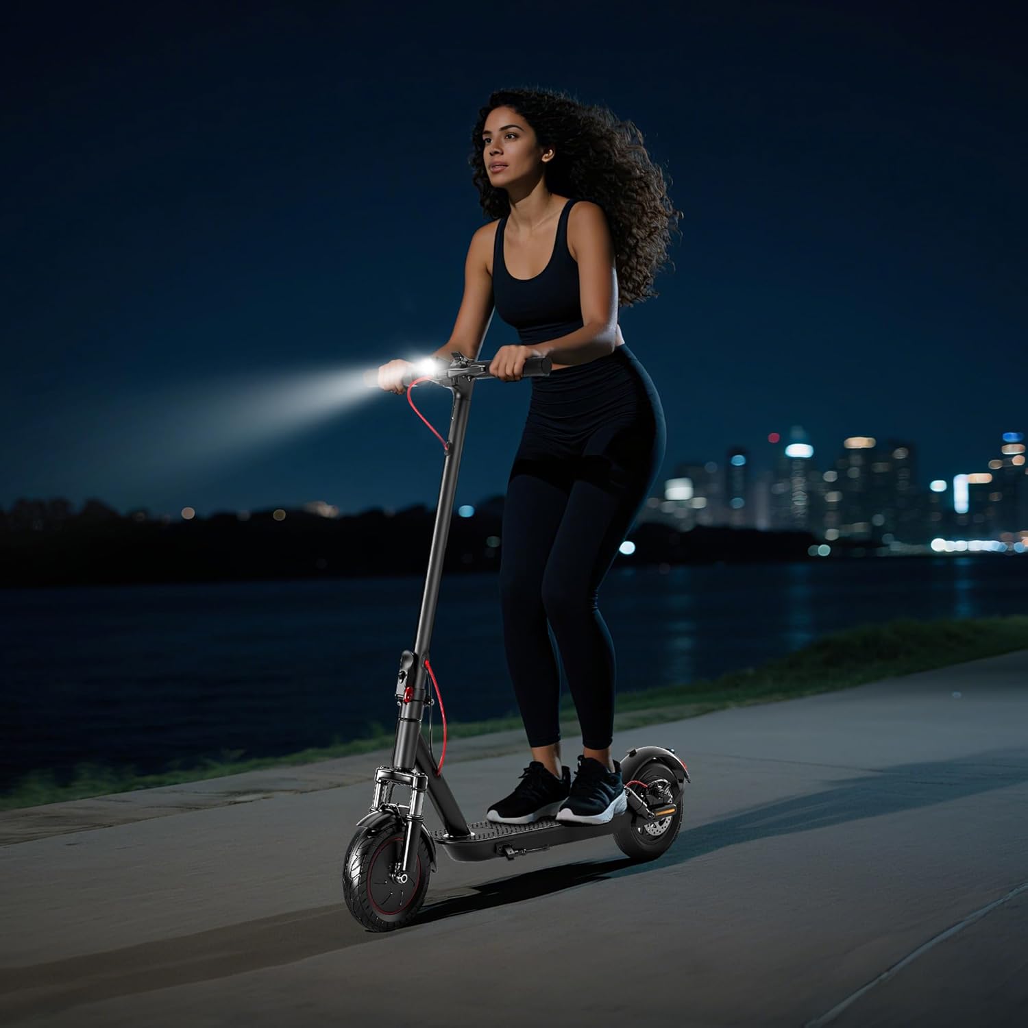 A person riding the Mankeel MK083 Electric Scooter at night, with the bright front headlight illuminated.