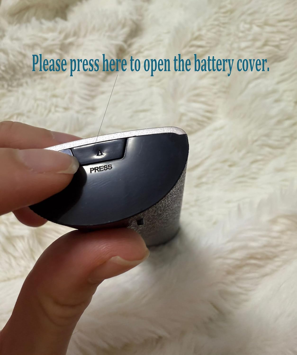 Hand pressing the battery cover release button on the remote control