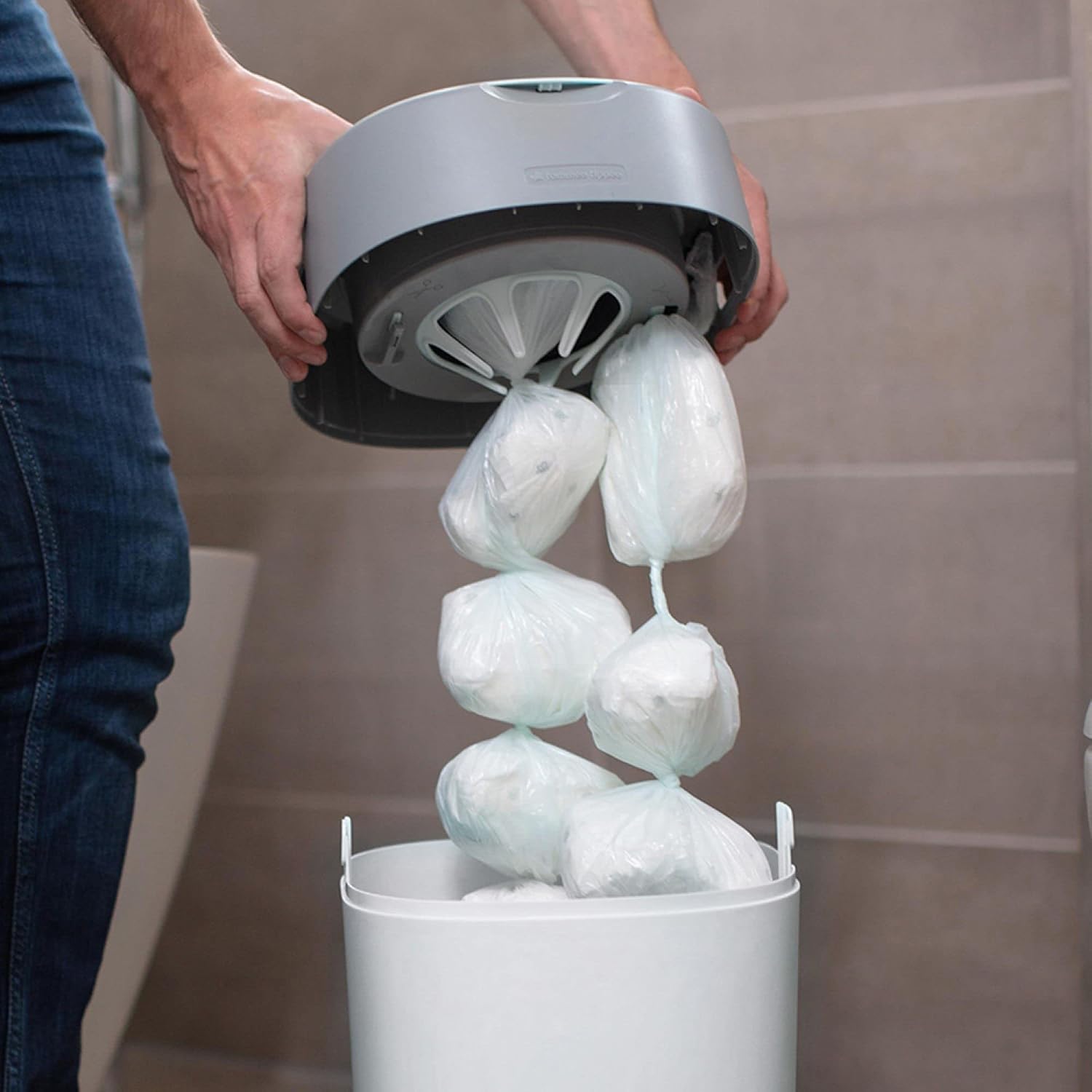 Hand pulling a chain of individually wrapped diapers from a diaper pail