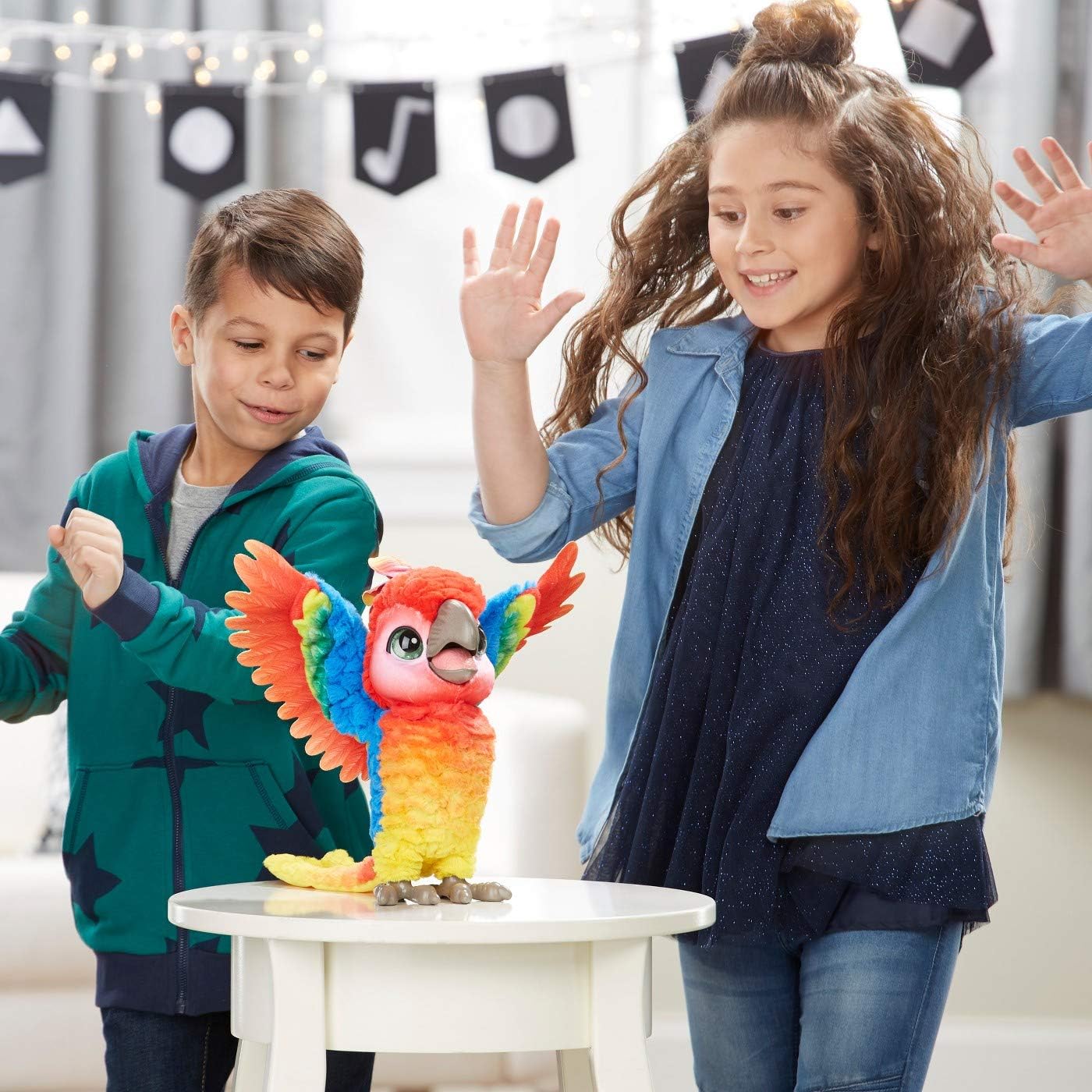 A boy and a girl dancing alongside the FurReal Pauli parrot, which is also in a dancing pose.