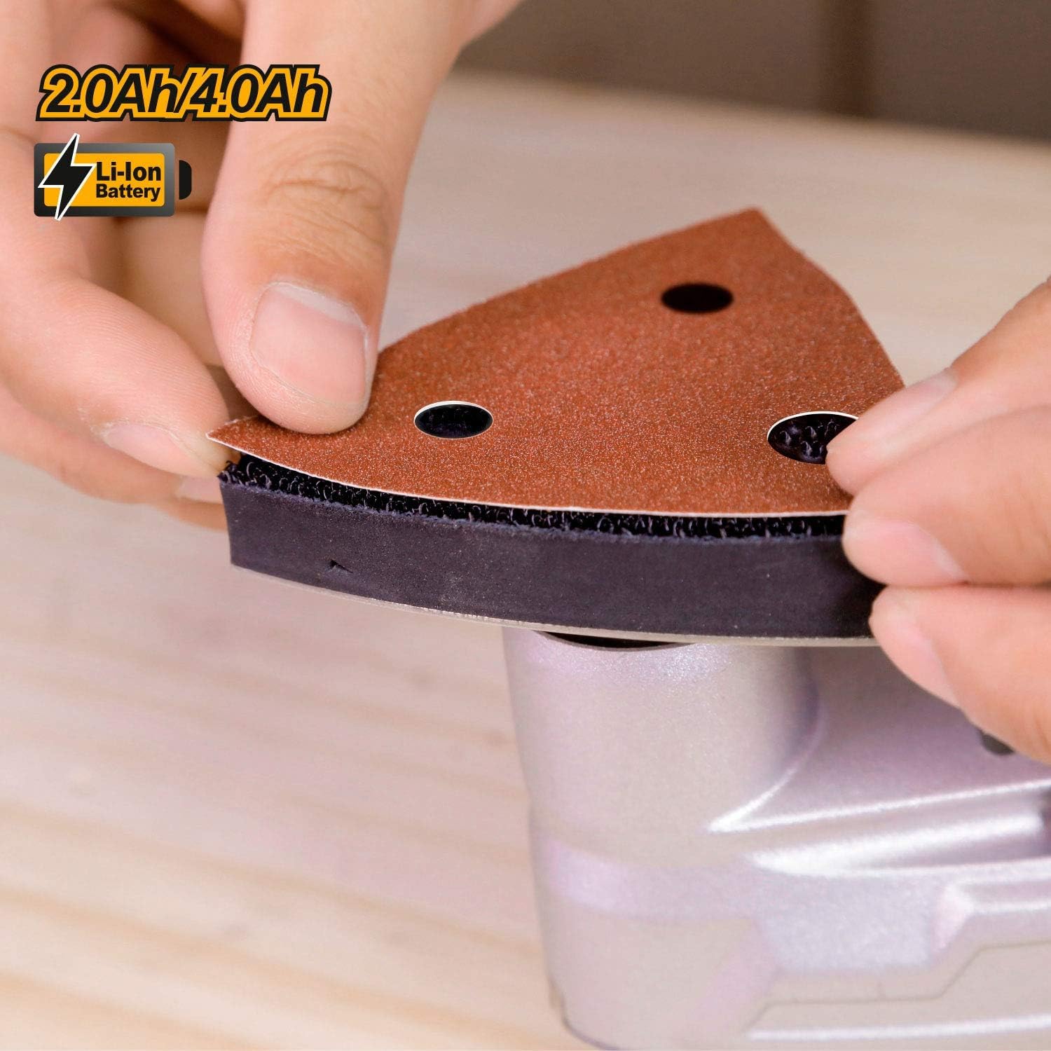 Hands attaching a triangular sandpaper sheet to the sanding base of the multi-tool