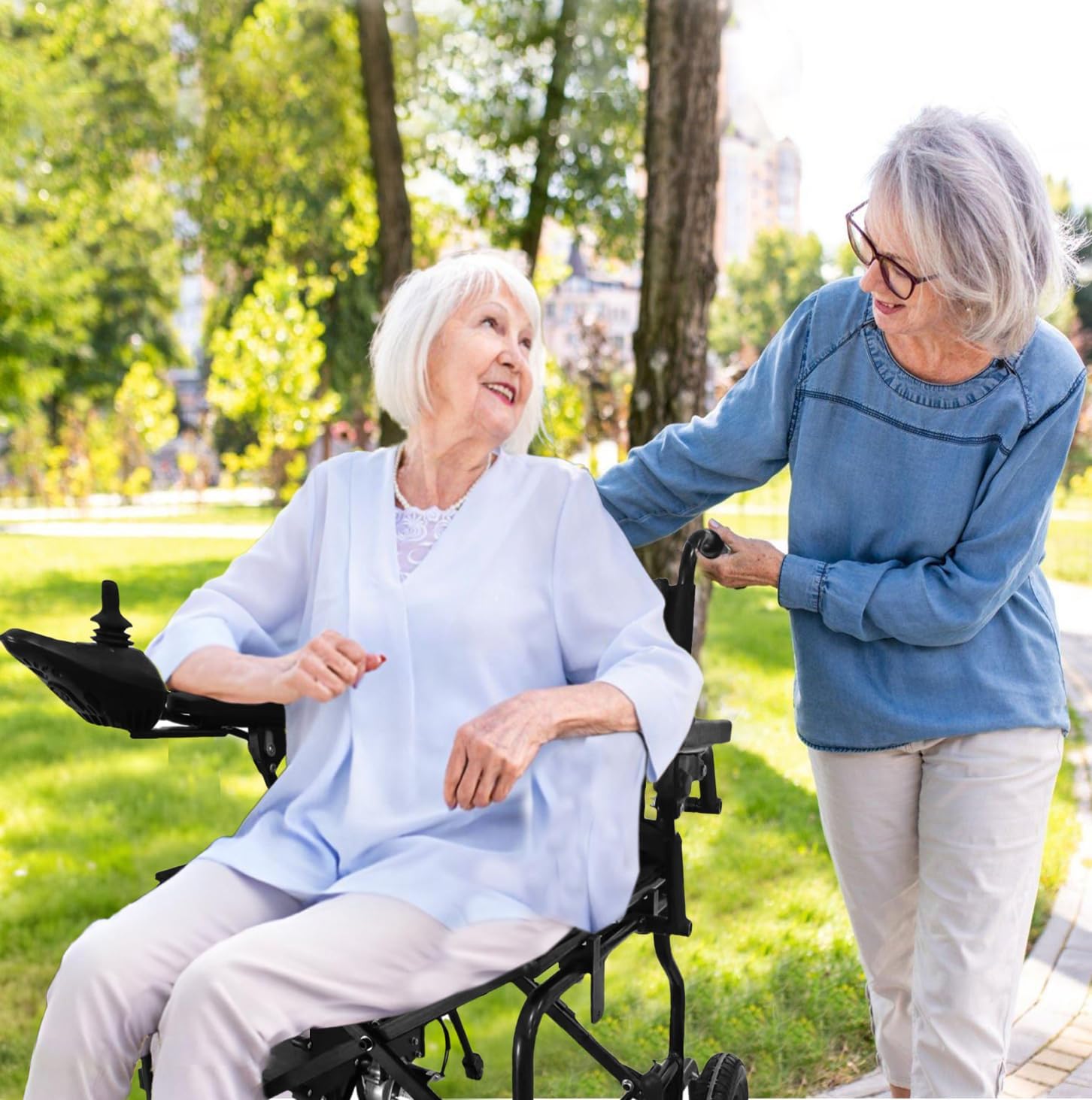A person using the LiteRide wheelchair in a park, being pushed by another person