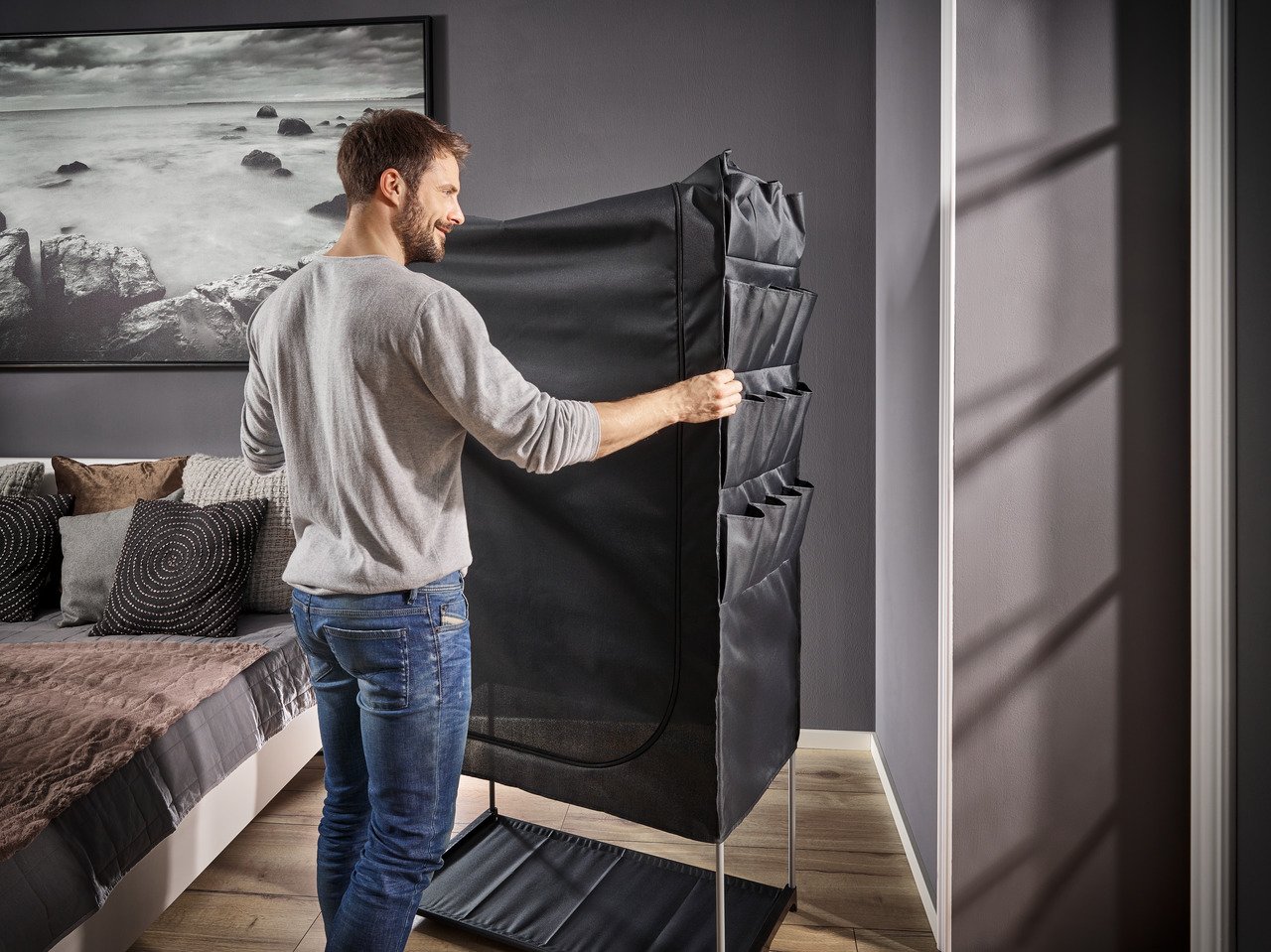 Persoon die het frame van de Leifheit draagbare stoffen kledingkast in elkaar zet.