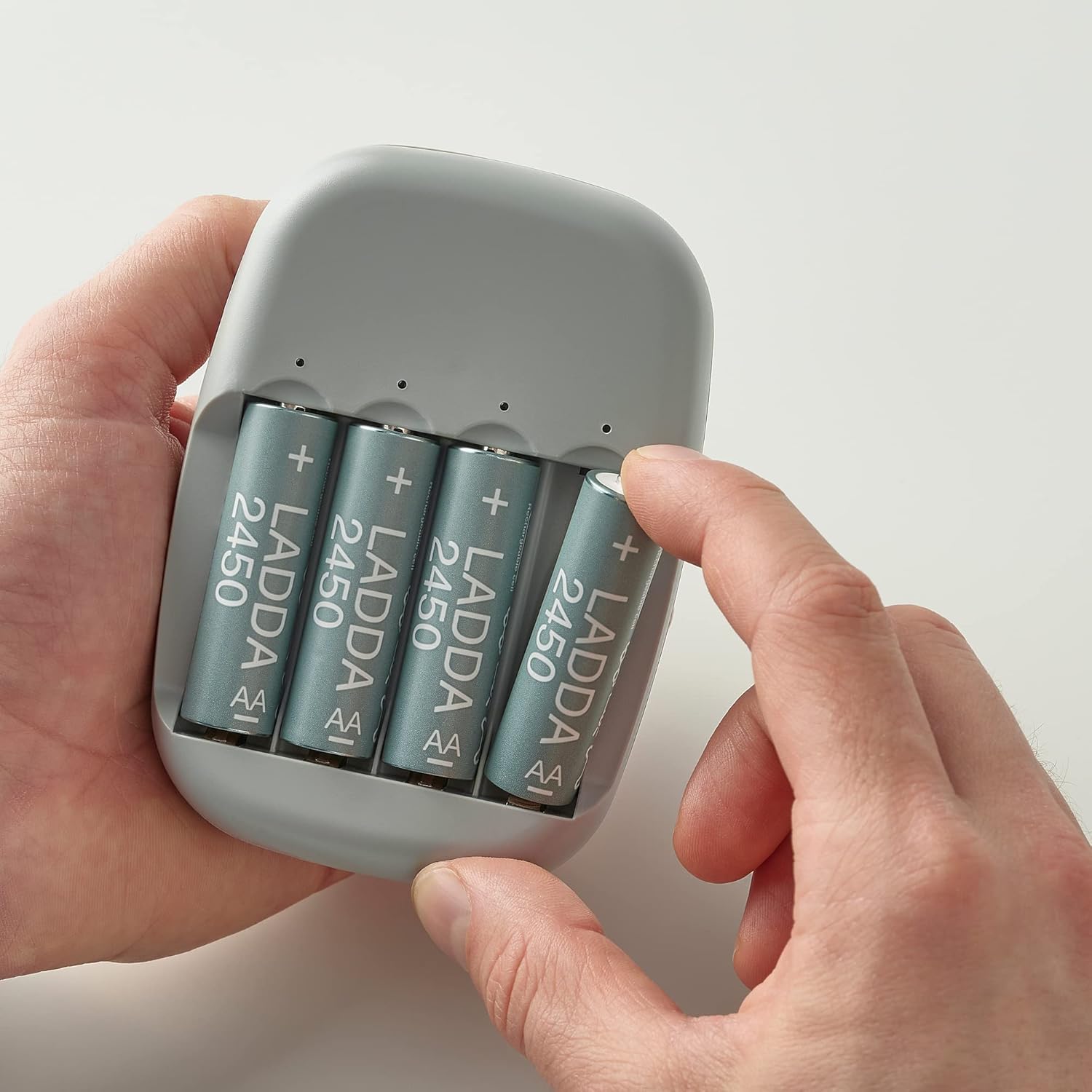 Hand inserting a battery into the IKEA STENKOL Battery Charger