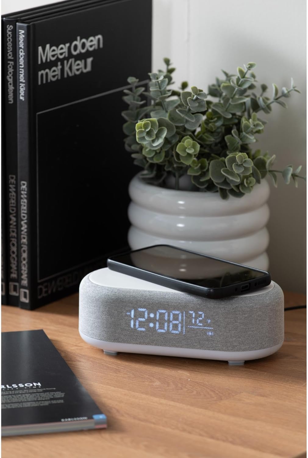 Karlsson Vogue Alarm Clock on a nightstand with a smartphone charging on its top surface.
