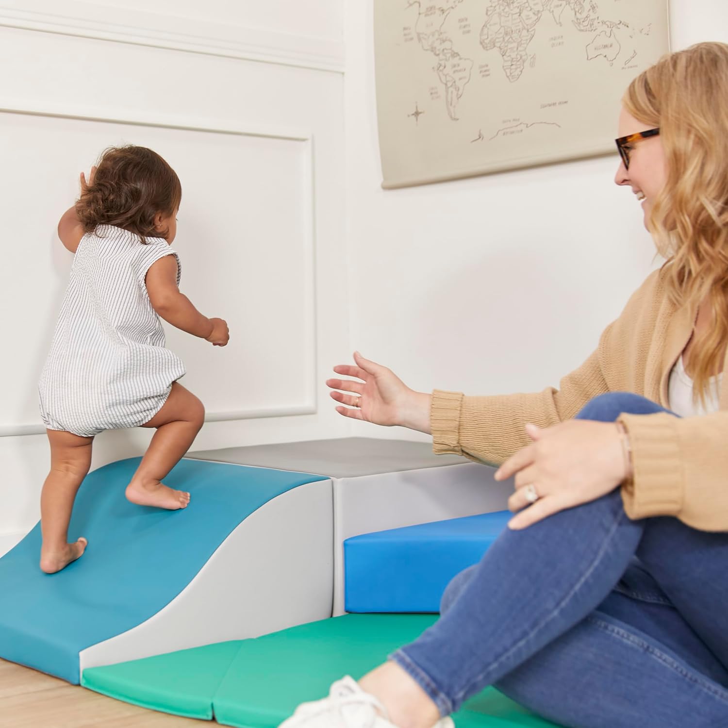 Toddler climbing onto a foam block with adult assistance