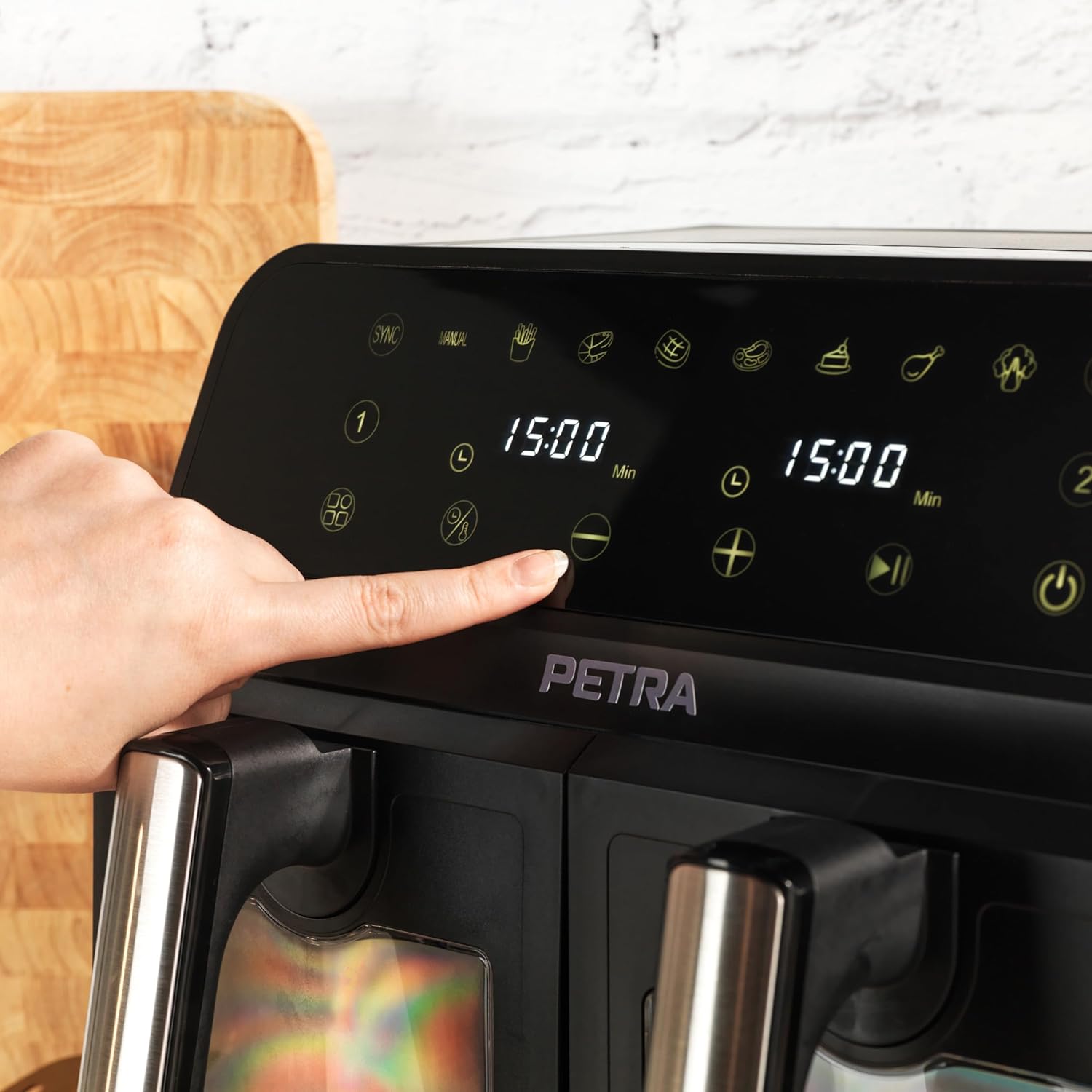 A hand stirring food in one of the Petra PT5196GWVDE Dual Air Fryer's baskets