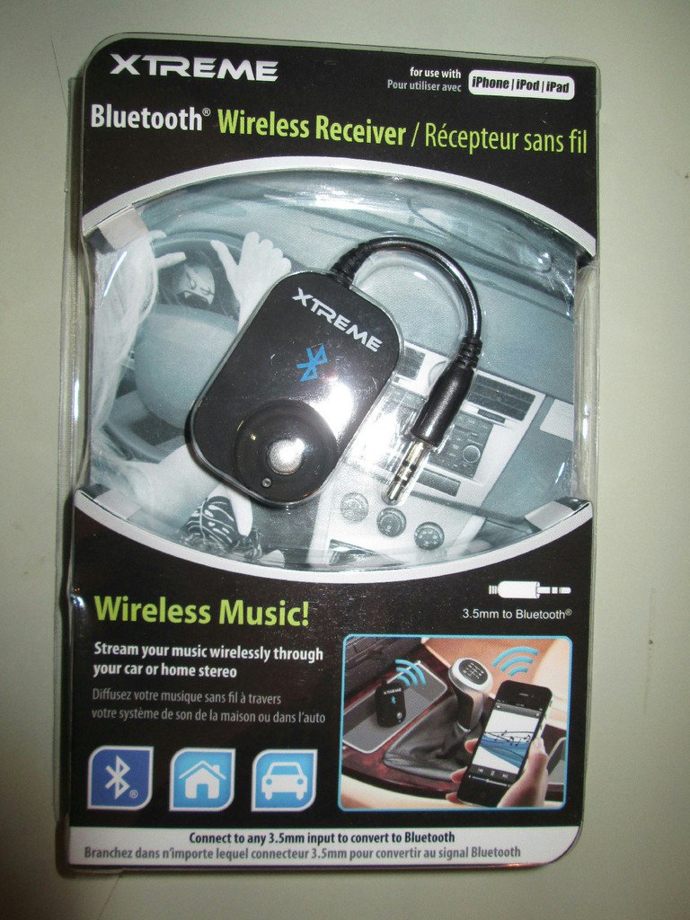 Xtreme Bluetooth Wireless Music Receiver connected to a car's auxiliary input, streaming music from a smartphone.