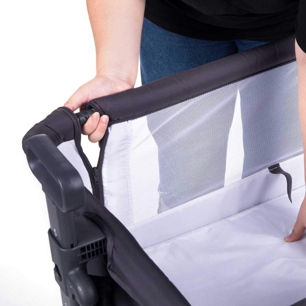 Hand unzipping the side panel of the bassinet