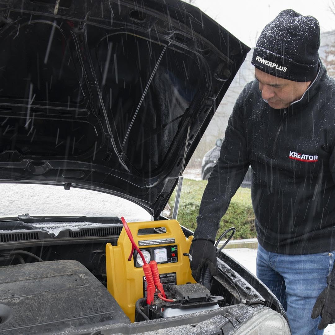 A person jump starting a car in snowy conditions, demonstrating the Powerstation's utility in adverse weather.