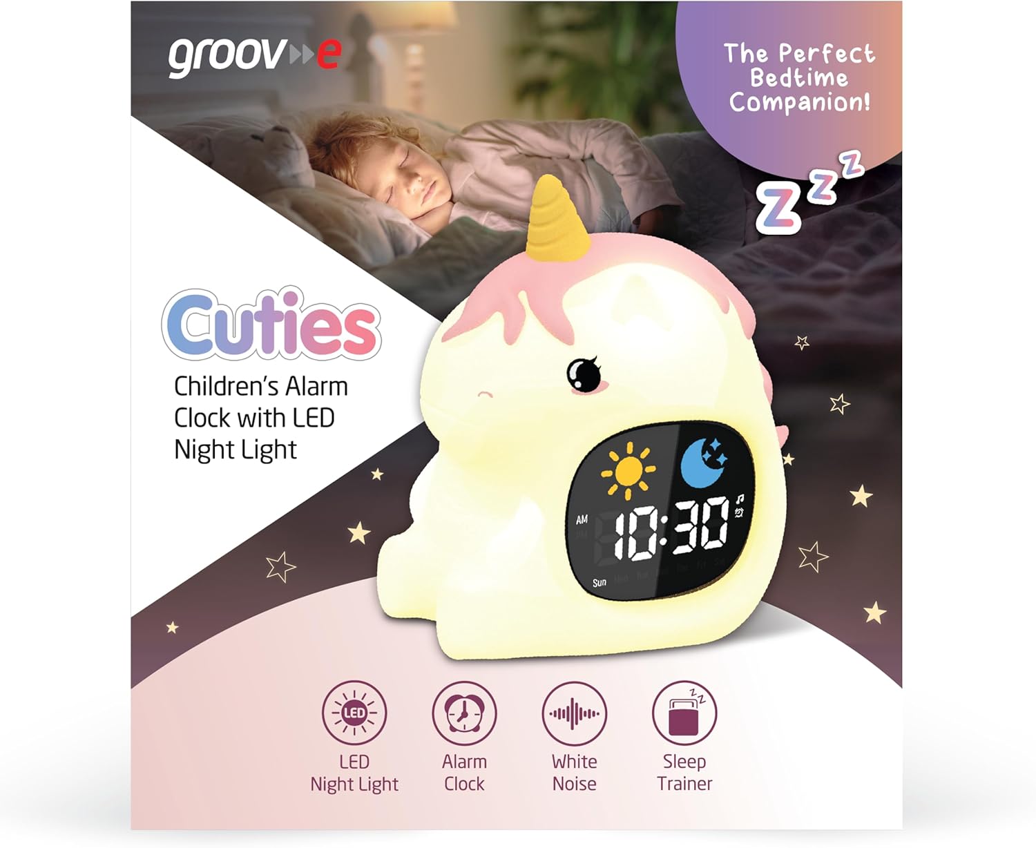 groov e Cuties Sleep Trainer Alarm Clock on a bedside table in a dimly lit room, showing the time and a glowing sun icon, indicating wake-up time.
