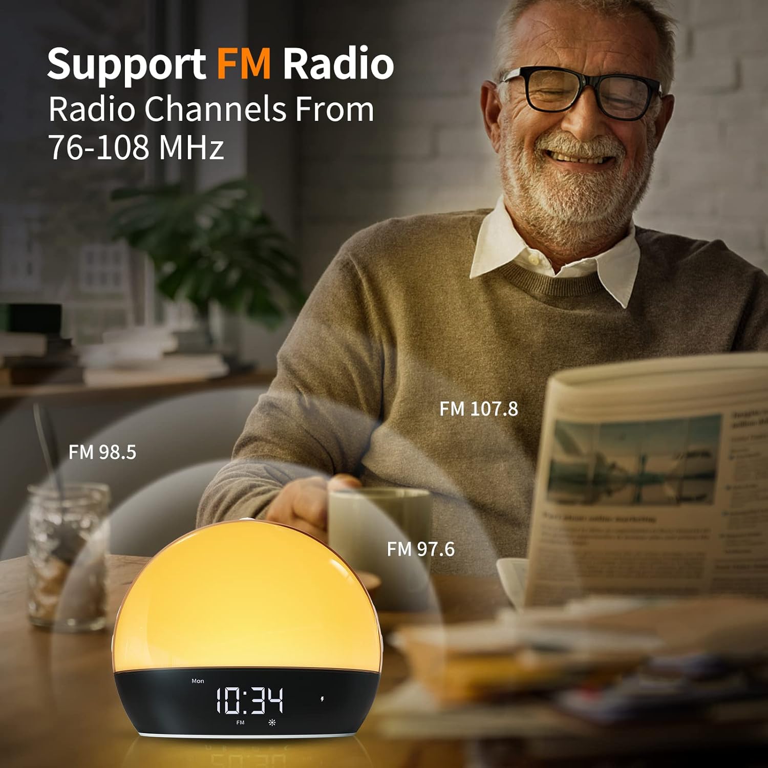 An elderly man reading a newspaper with the Cabtick Sunrise Alarm Clock on a table, indicating FM radio support with various frequencies.