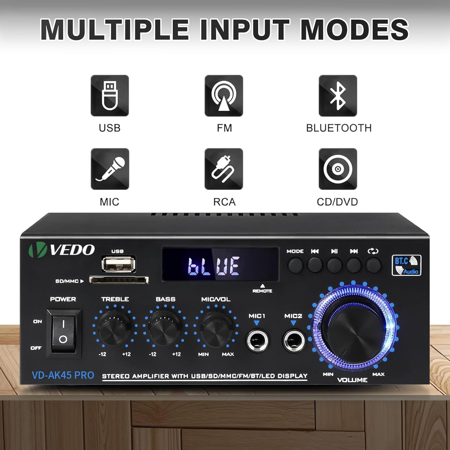 Amplificador em vista frontal sobre uma superfície de madeira, em ambiente interno.